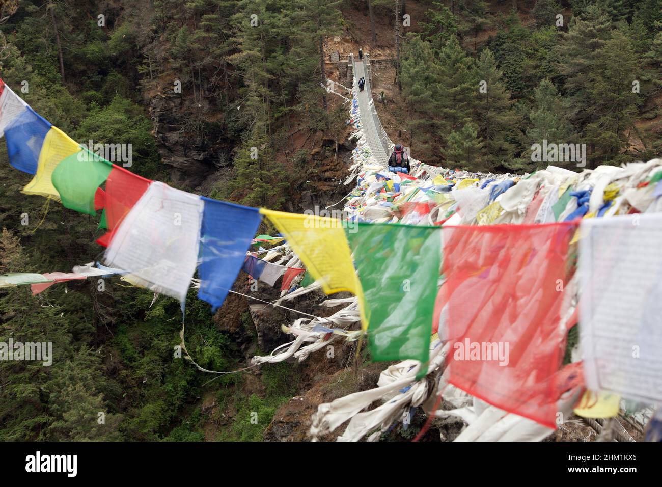 Ponte sospeso per la caccia alla corda con una fila di bandiere di preghiera sotto il villaggio di Namche Bazar, strada per il campo base Everest, Nepal Foto Stock