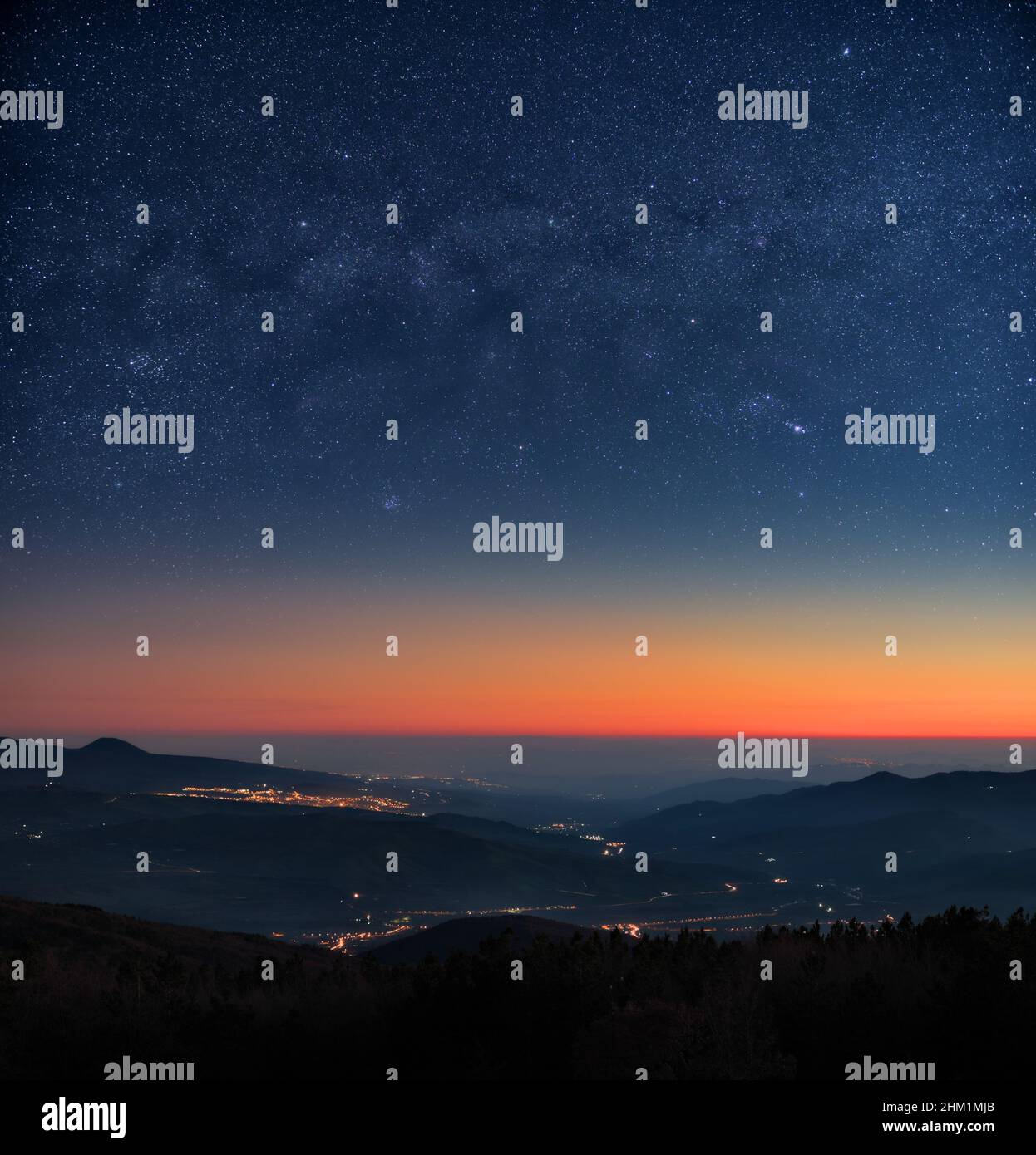paesaggio di cielo stellato notte con le luci della città e i colori del crepuscolo all'orizzonte Foto Stock