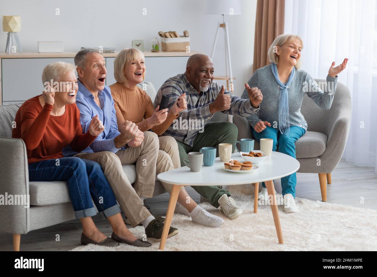 Gli anziani emotivi guardano la televisione in salotto Foto Stock