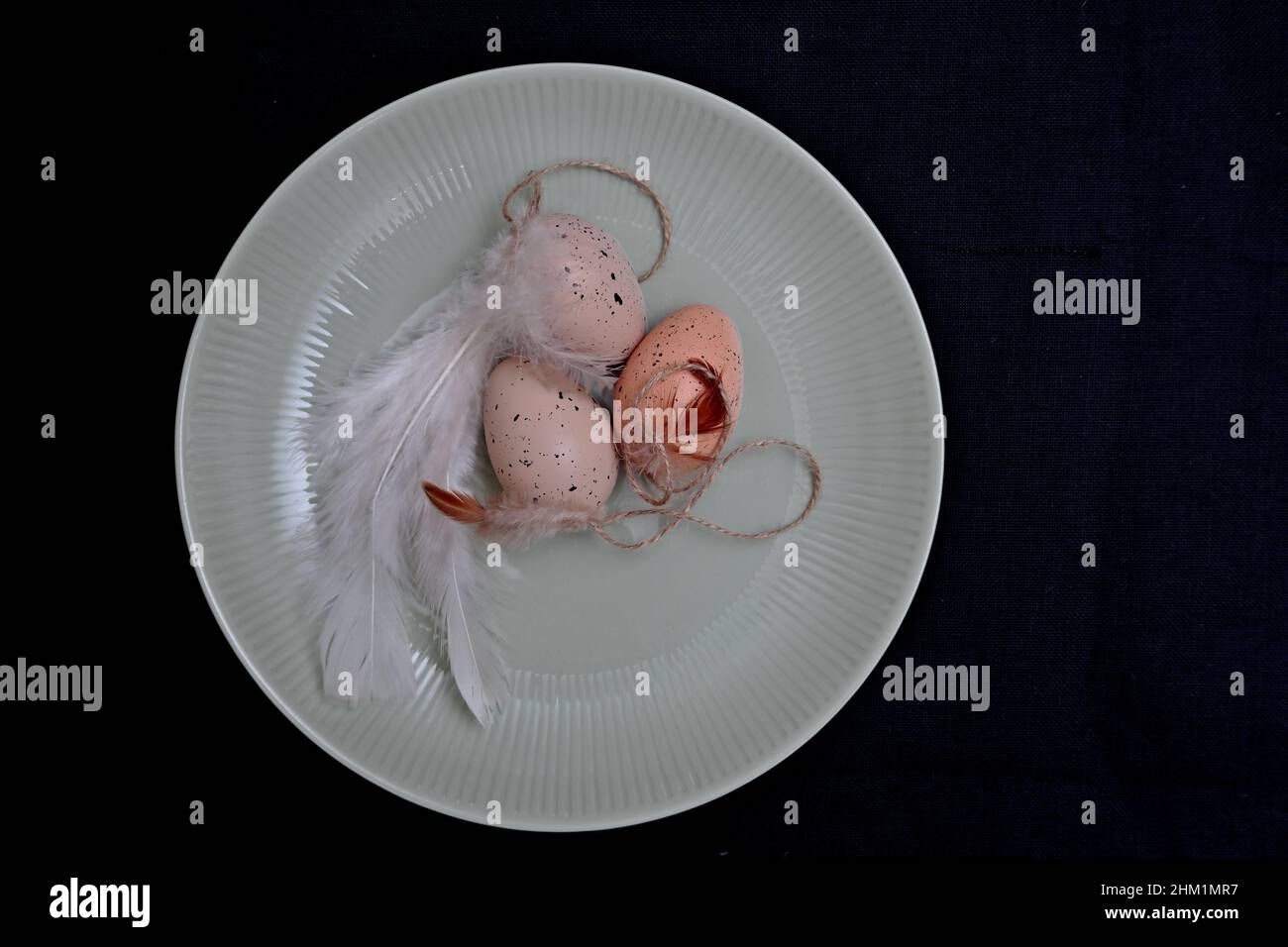 Uova di Pasqua marroni e piume bianche su un piatto verdastro Foto Stock