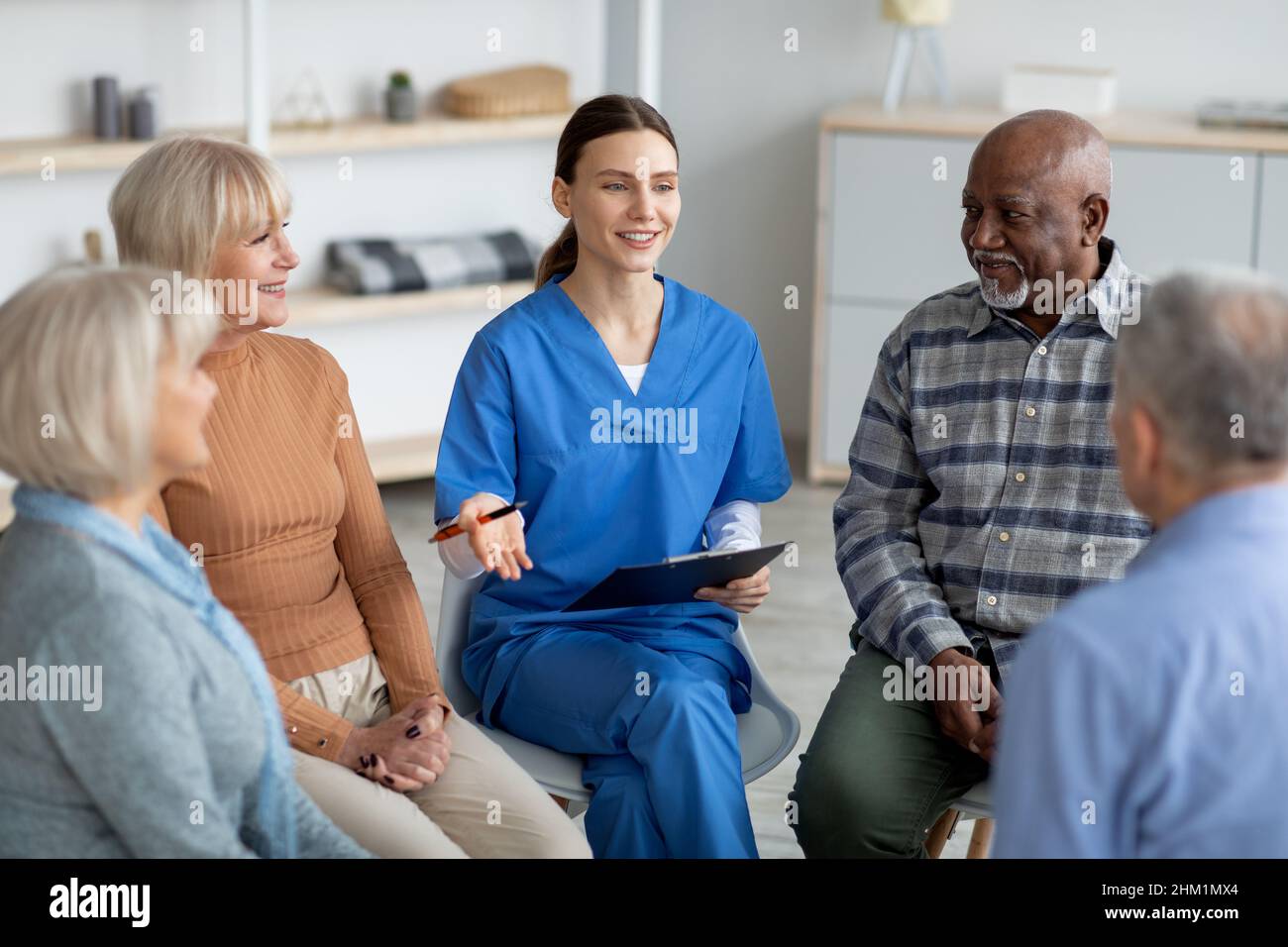 Psicologa giovane amichevole che ha conversato con gli anziani Foto Stock