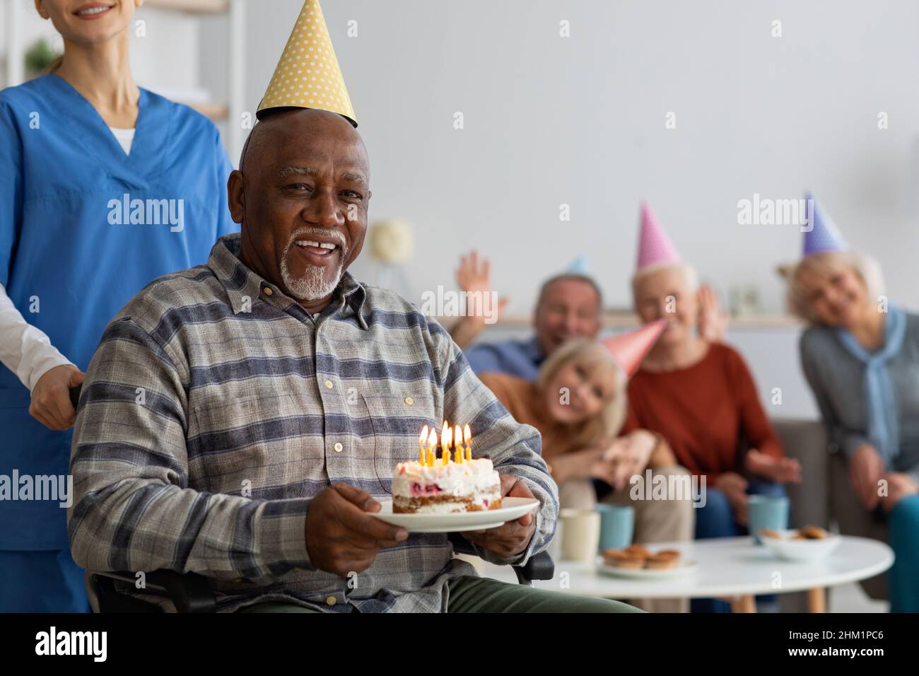 Uomo nero in sedia a rotelle festeggia il compleanno nella casa di cura Foto Stock