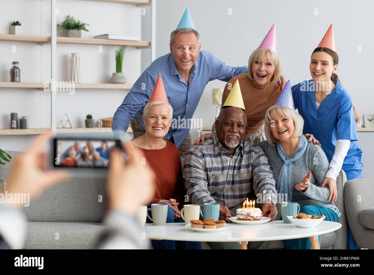Persone anziane e infermieri positivi festeggiano il compleanno, scattando foto Foto Stock