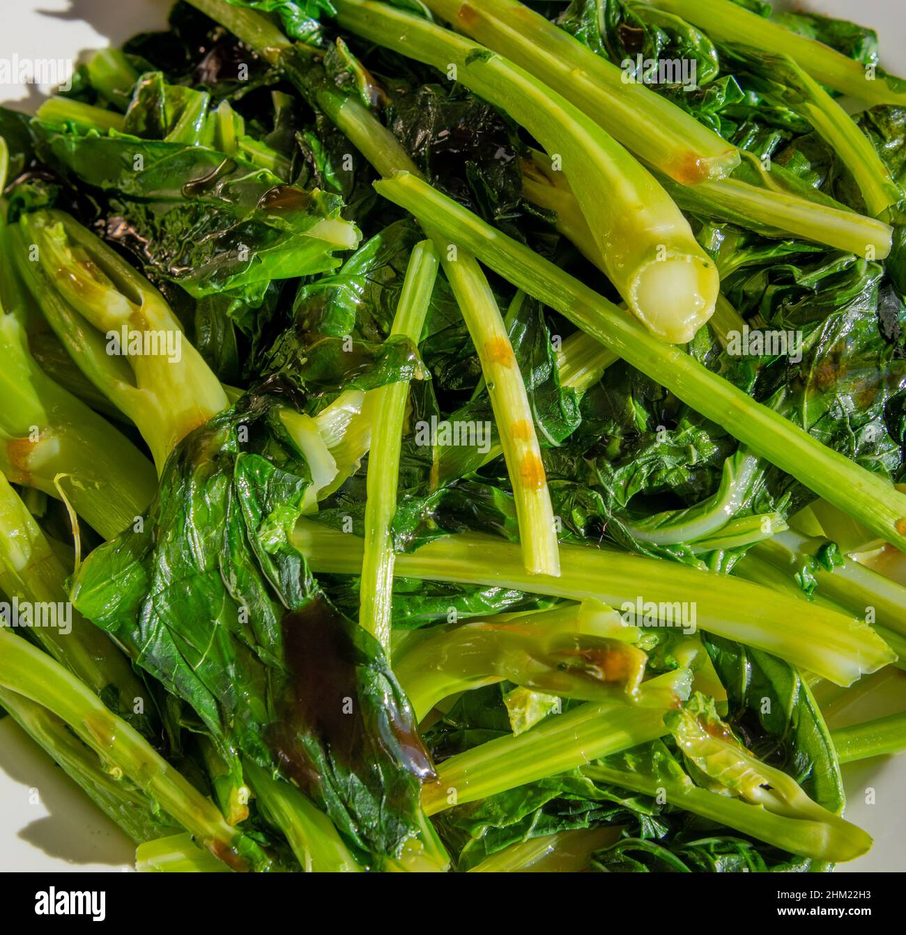 Primo piano di un piatto di Kai LAN fresco, una verdura cinese servita con una spruzzata di olio di sesamo e salsa di ostriche. Foto Stock
