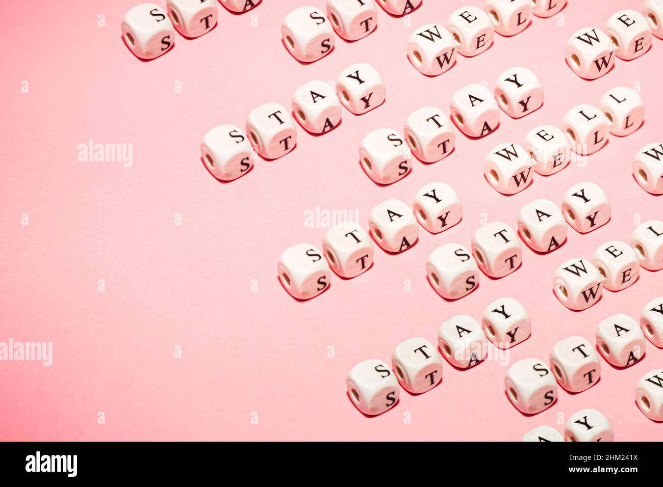 Dici bianchi su sfondo pastello rosa con messaggio Stay Well, pattern ripetitivo, minimalistico, wellness e concetti di vita con spazio copia Foto Stock