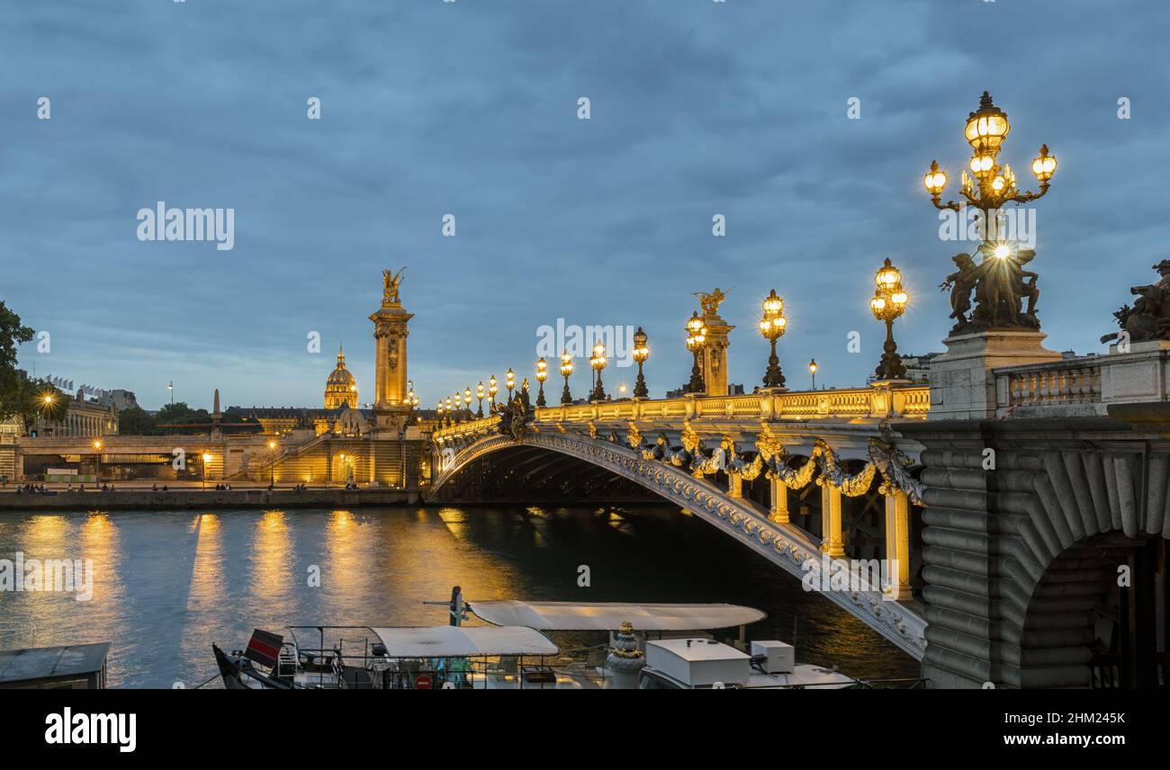 Ponte Alexandre III sul fiume Senna e Hotel des Invalides al tramonto. Ponte decorato con lampade e sculture Art Nouveau ornate. Parigi, p. Foto Stock