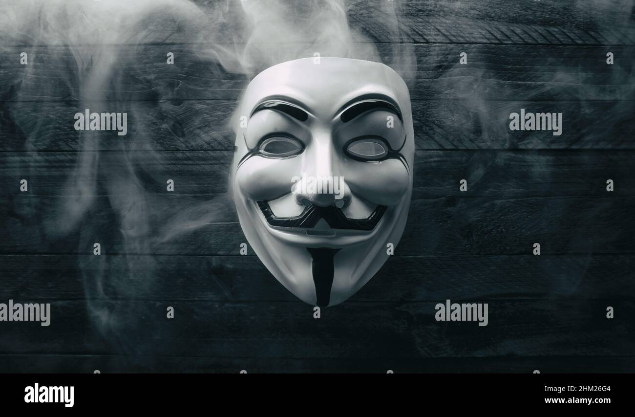 Studio girato di una maschera anonima vendetta con fumo su legno Foto Stock