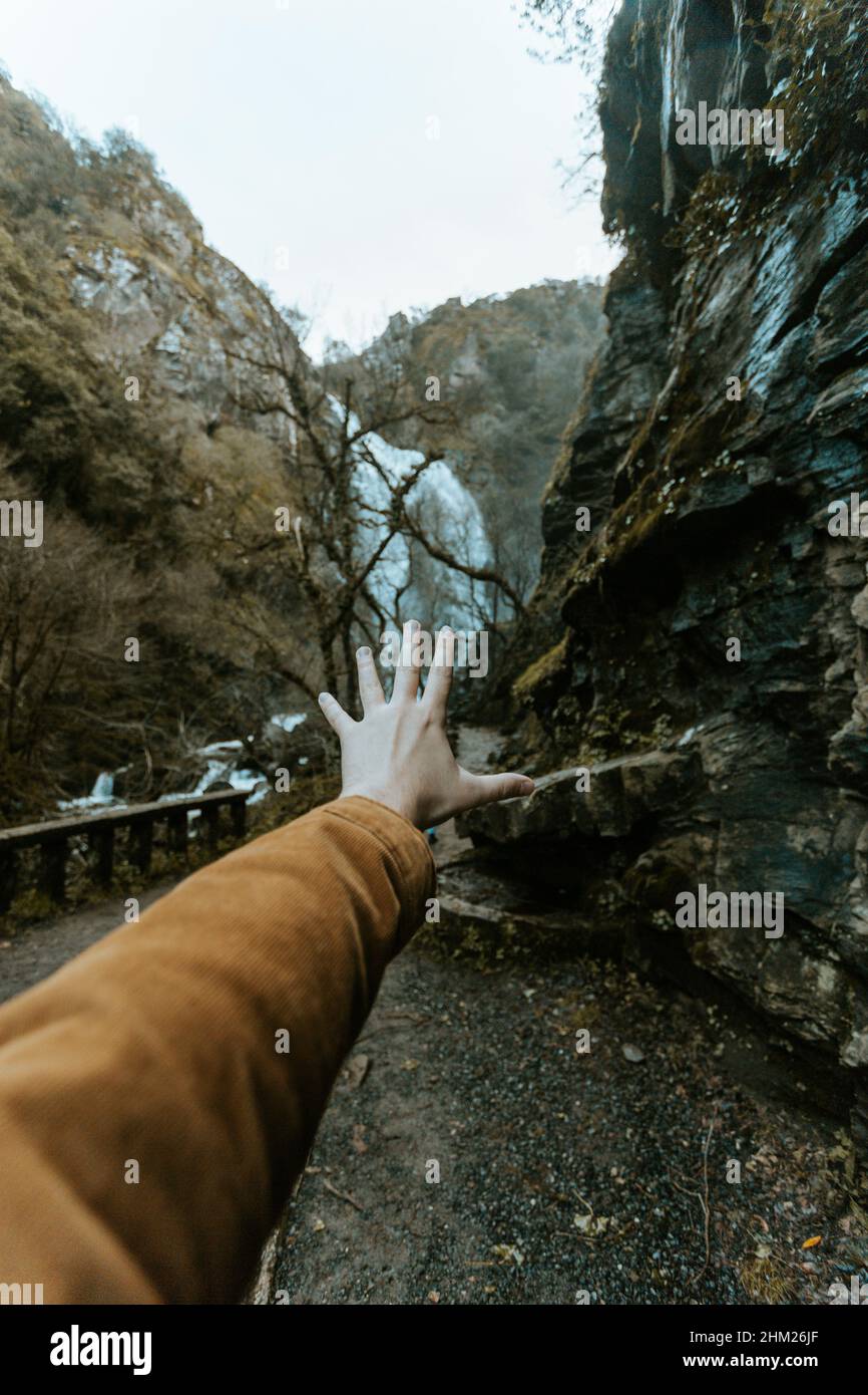 Una mano di fronte a una cascata massiccia in toni modici con concetto liberty e viaggiare su toni vintage con spazio copia Foto Stock