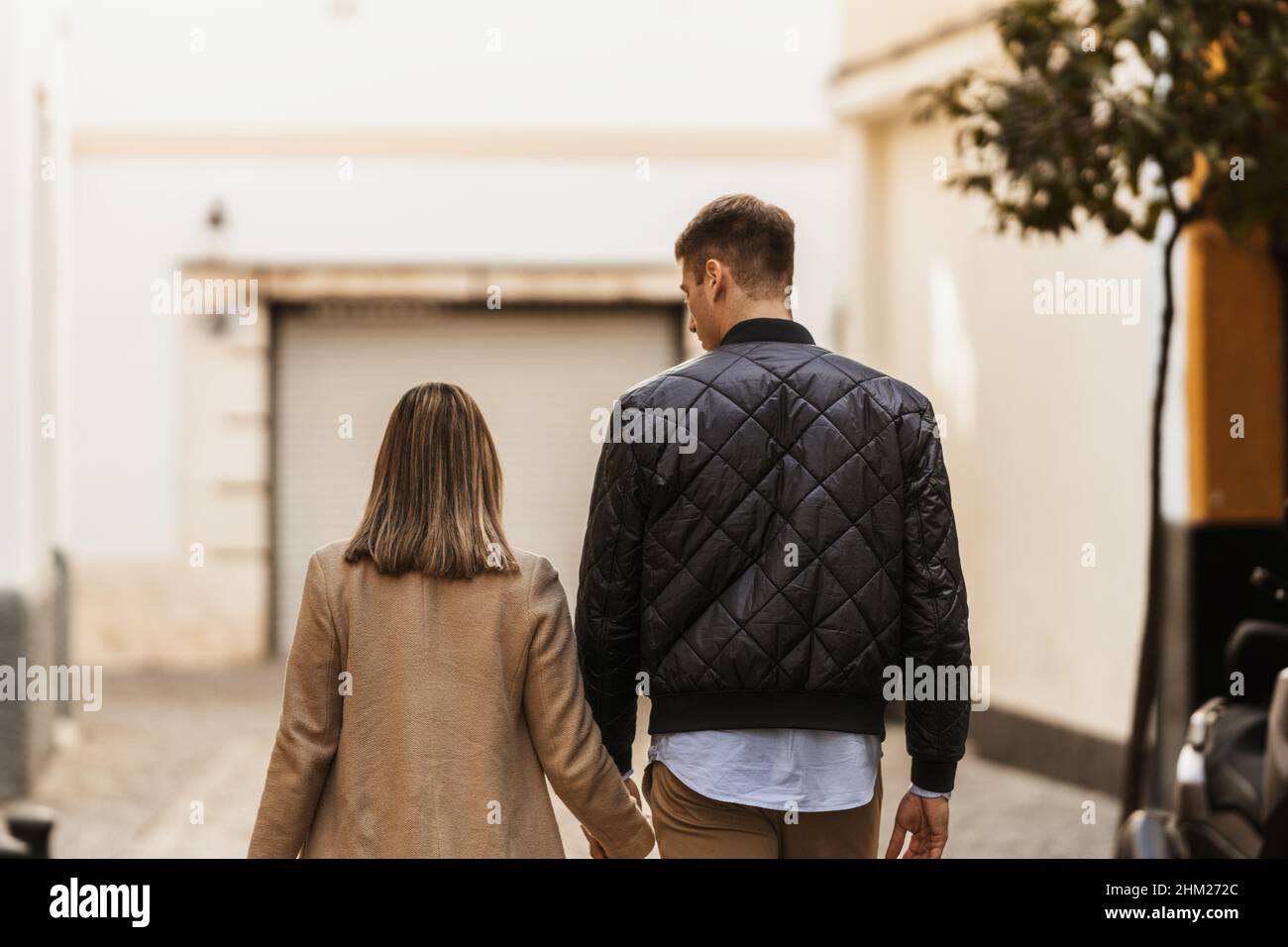 Vista posteriore di una sposa e sposo passeggiando per le strade di una città. Foto Stock
