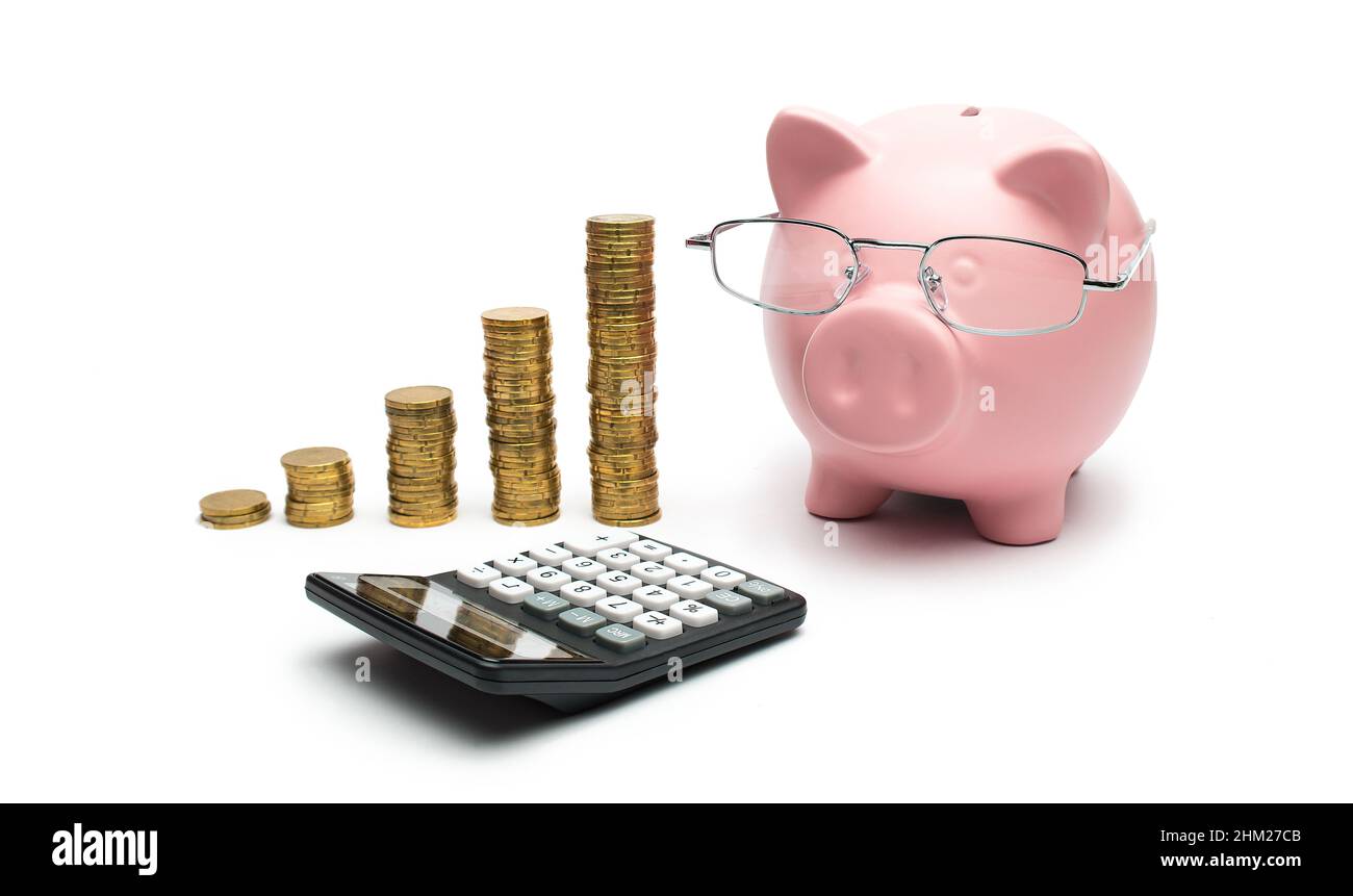 Banca Piggy rosa con calcolatrice e monete impilate Foto Stock
