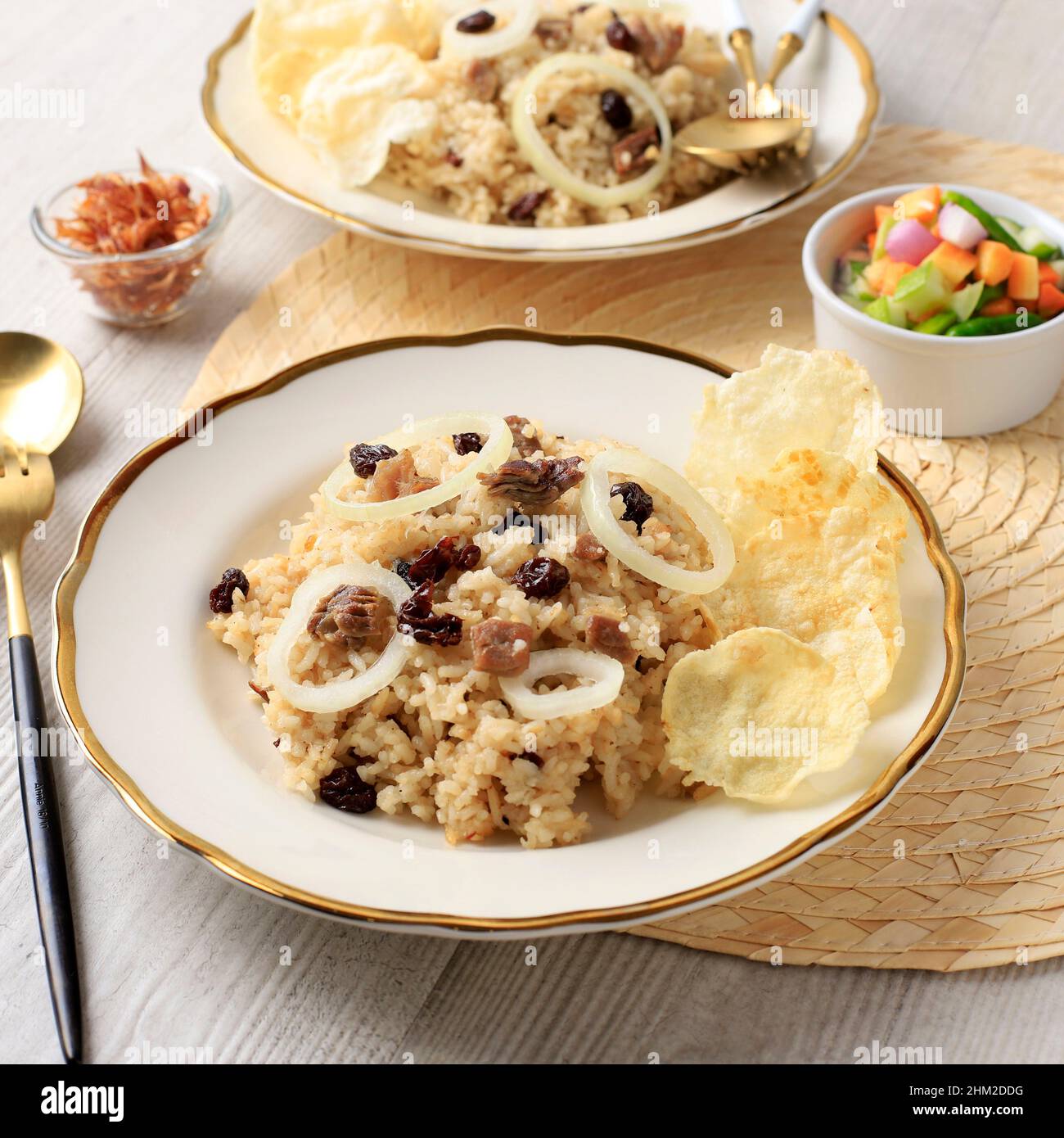 Nasi Kebuli, riso speziato arabo con carne di agnello e Raisin. Speziato con cannella, chiostro, anice stellato. Servd on Cream Ceramic Plate with Golden Rim. usu Foto Stock