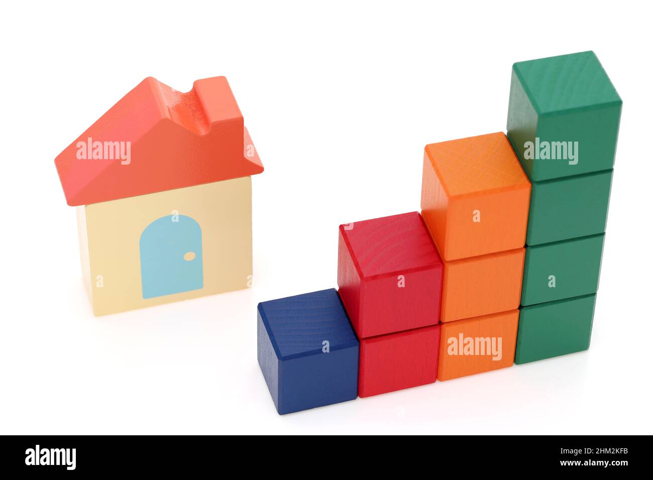 piccola casa giocattolo e blocchi di legno colorato su sfondo bianco Foto Stock