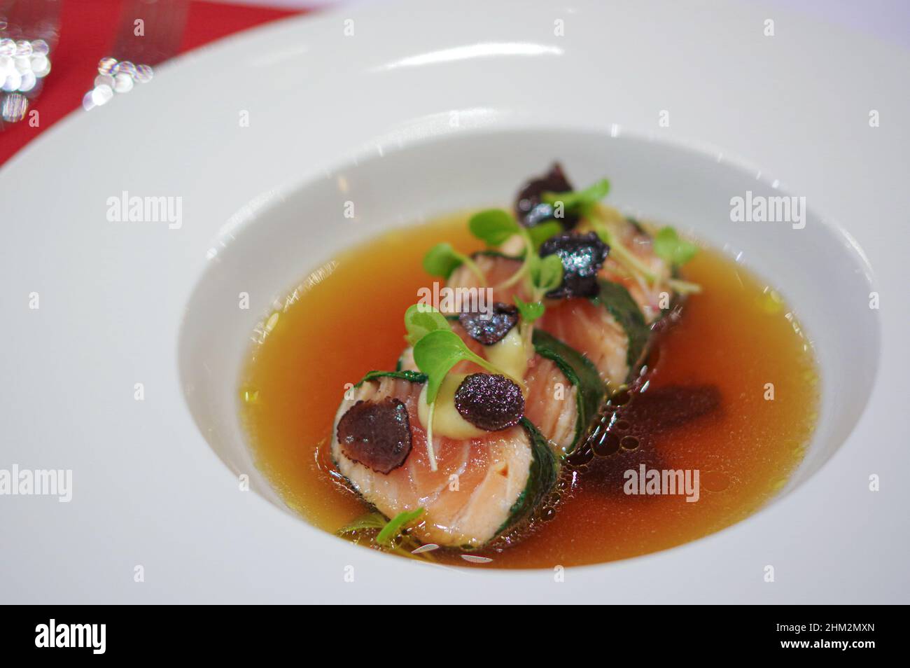 Rotolo di salmone confezionato a Nori con tartufo nero affettato e germogli nel piatto della ciotola per zuppa Foto Stock