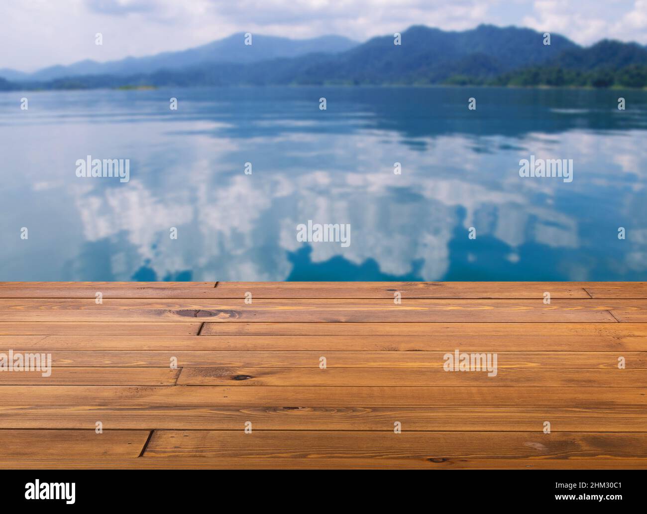 Bella tavola o pavimento in legno di legno marrone, superficie poco lucida, vista prospettica, sfondo di paesaggio di montagna e lago sfocato, riflesso di c Foto Stock