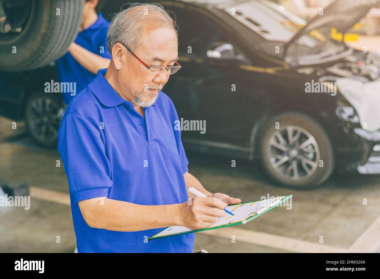 Proprietario di garage asiatico professionale adulto che lavora controllando la vettura del cliente Foto Stock