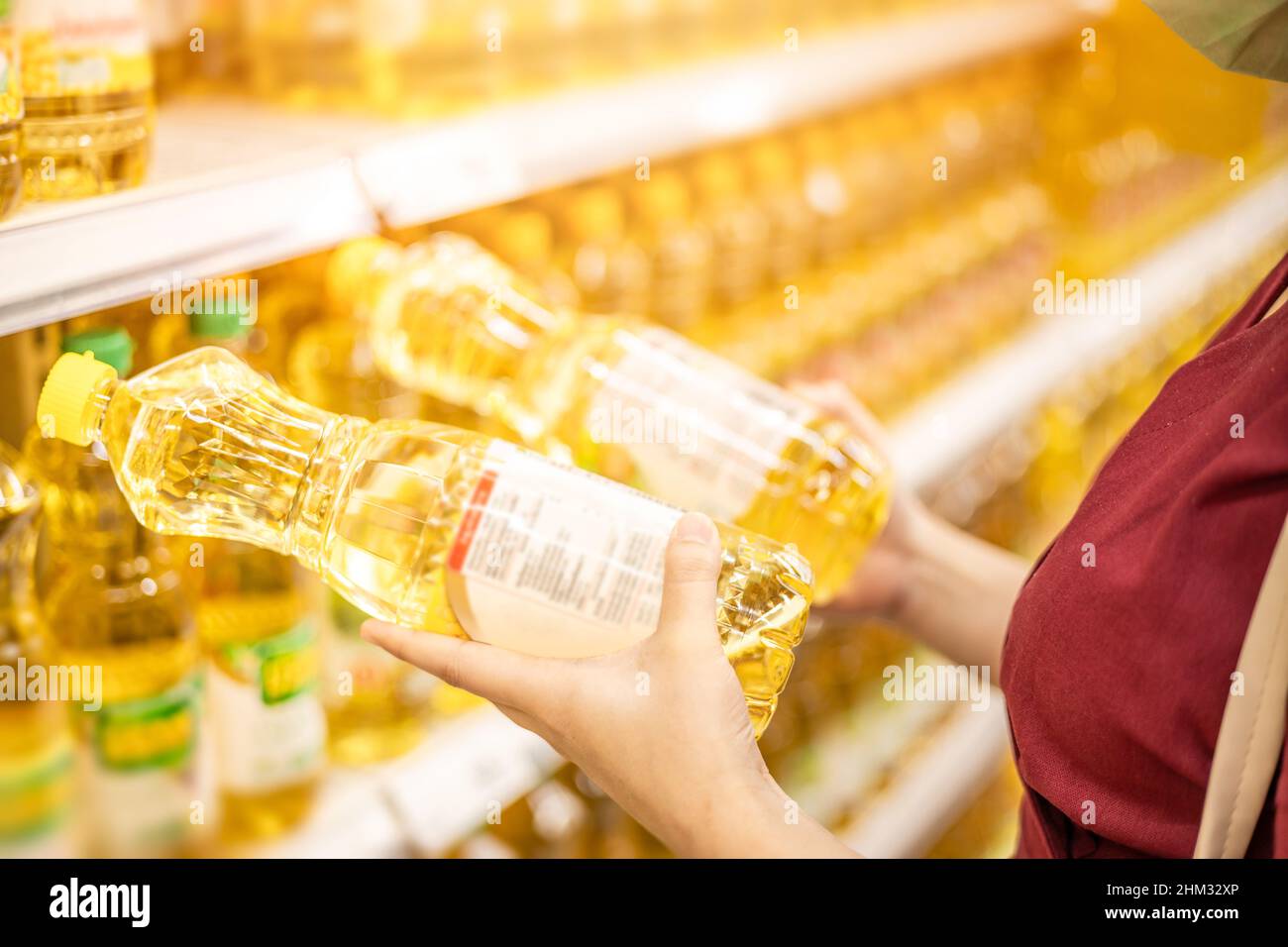 la gente che compra gli oli di cottura per l'alimento confronta e legge i prodotti etichetta di nutrizione nel supermercato Foto Stock