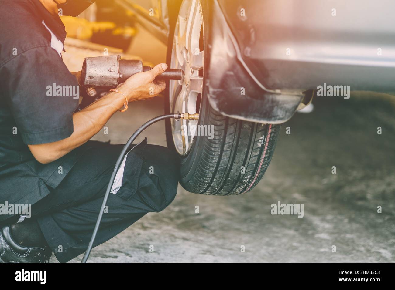 sostituzione della ruota del pneumatico dell'automobile e personale meccanico che lavora in garage Foto Stock