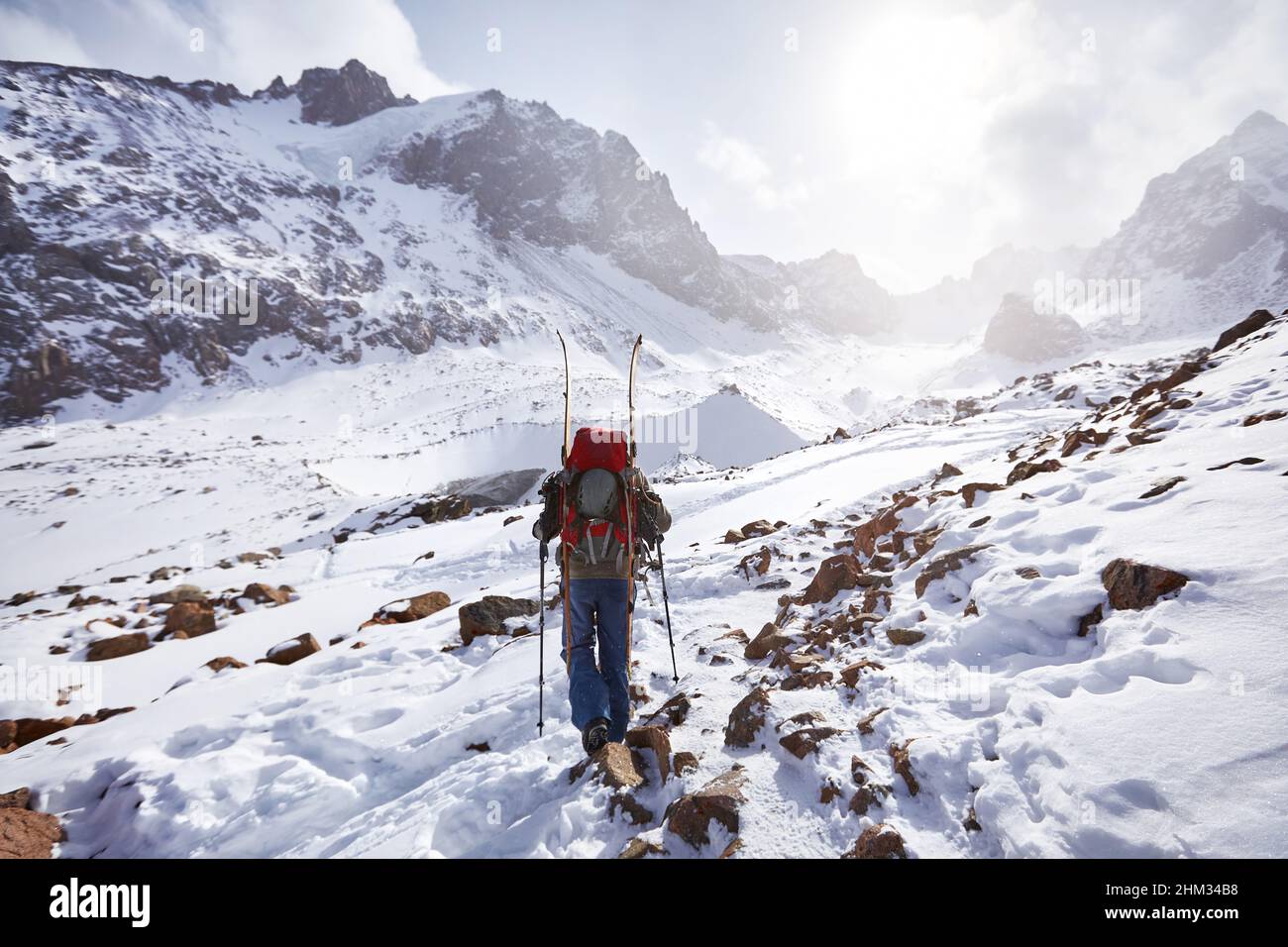 Sciatore uomo arrampicata con scissione tavola in alte montagne innevate. Sport all'aperto stagione invernale. Foto Stock