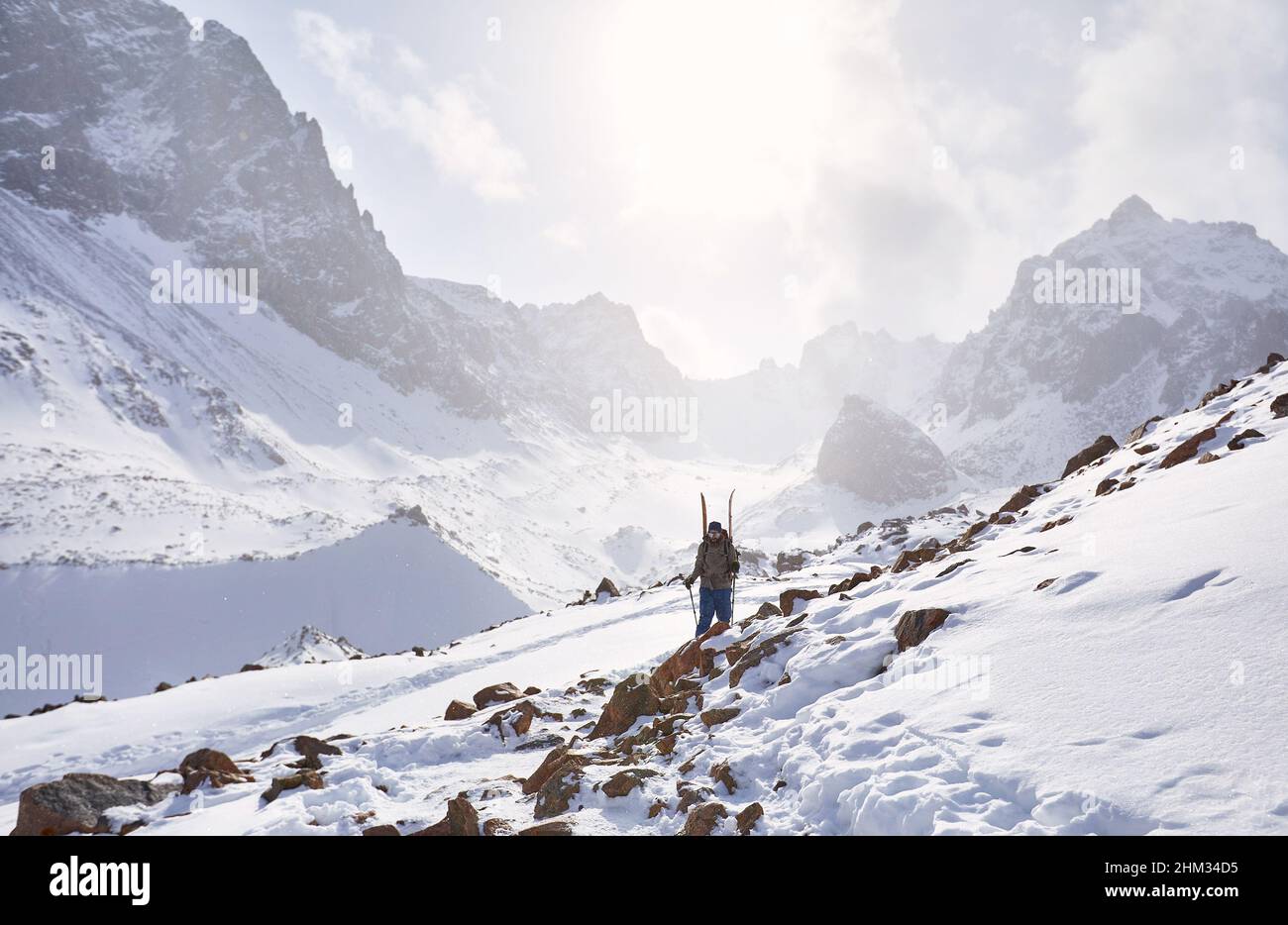 Sciatore uomo arrampicata con scissione tavola in alte montagne innevate. Sport all'aperto stagione invernale. Foto Stock