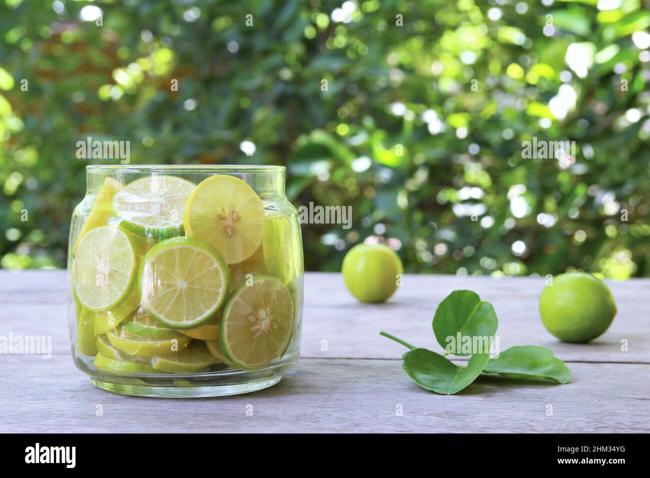 Un vaso di vetro di fette di lime su tavola di legno in giardino. Foto stock vista anteriore spazio copia Foto Stock