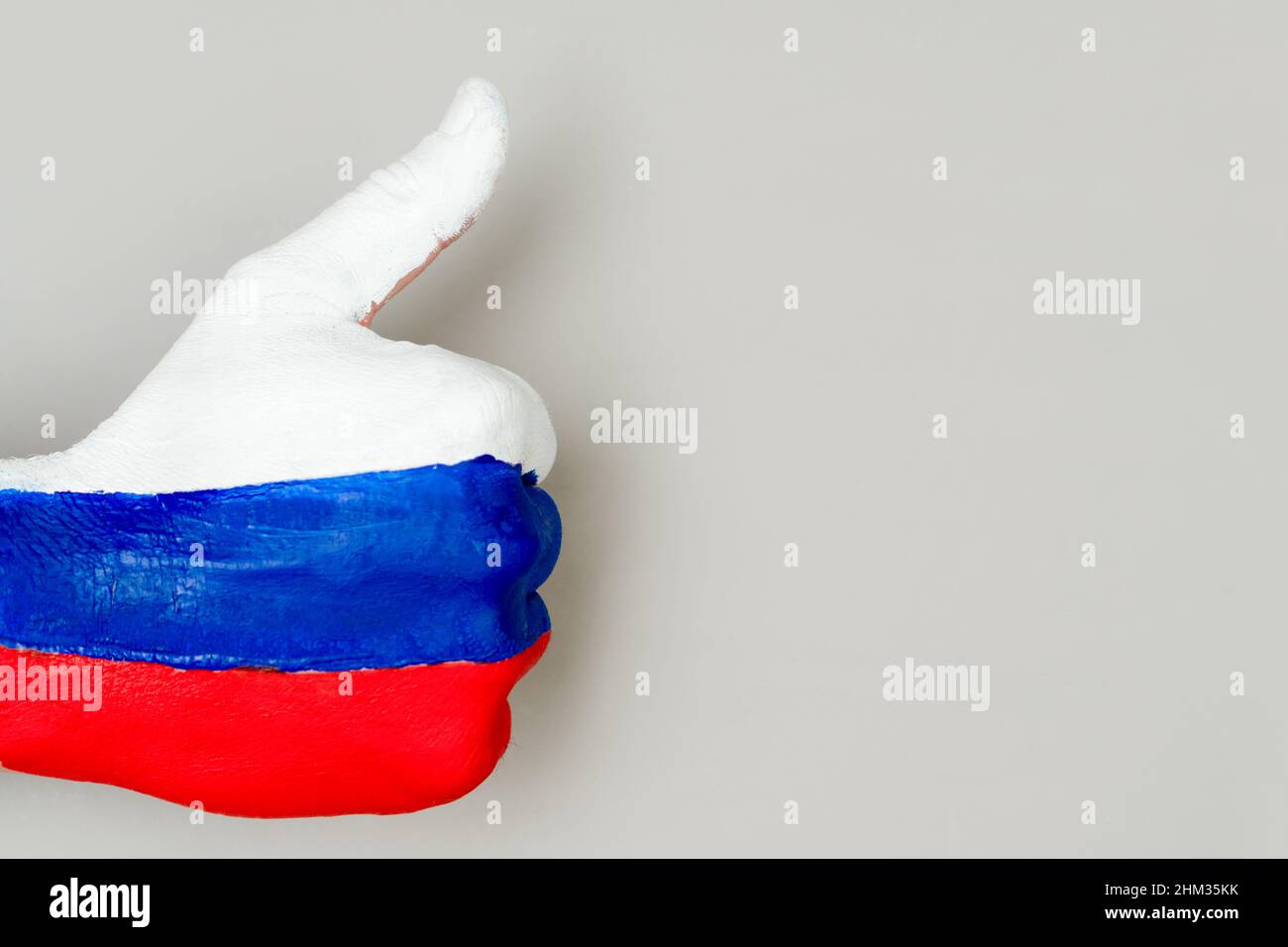 Pollice su mano di mano con il disegno di una bandiera della Russia su uno sfondo grigio. Foto Stock