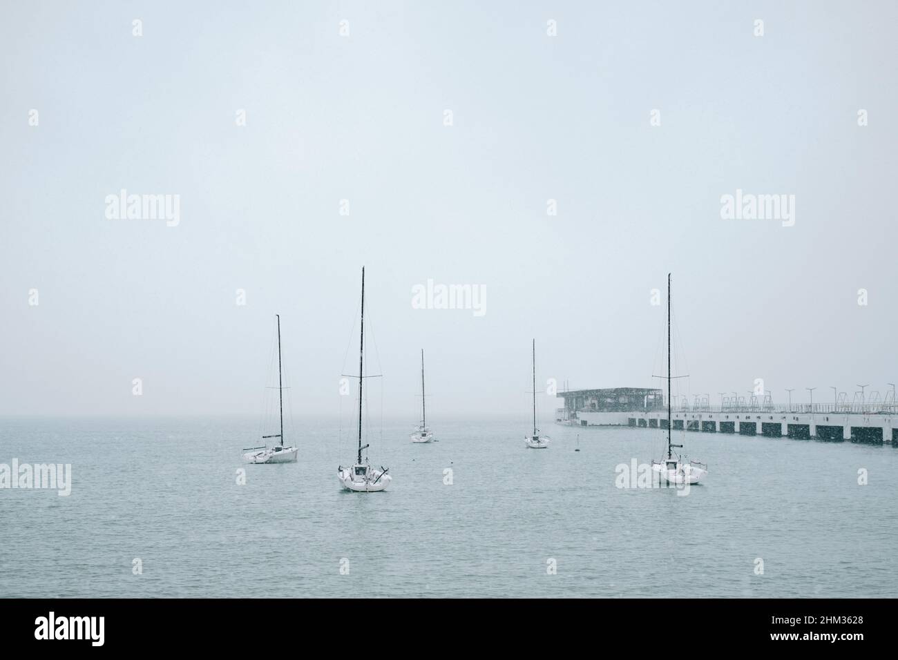 Diversi yacht a vela sono ormeggiati al molo in mare. Foto Stock
