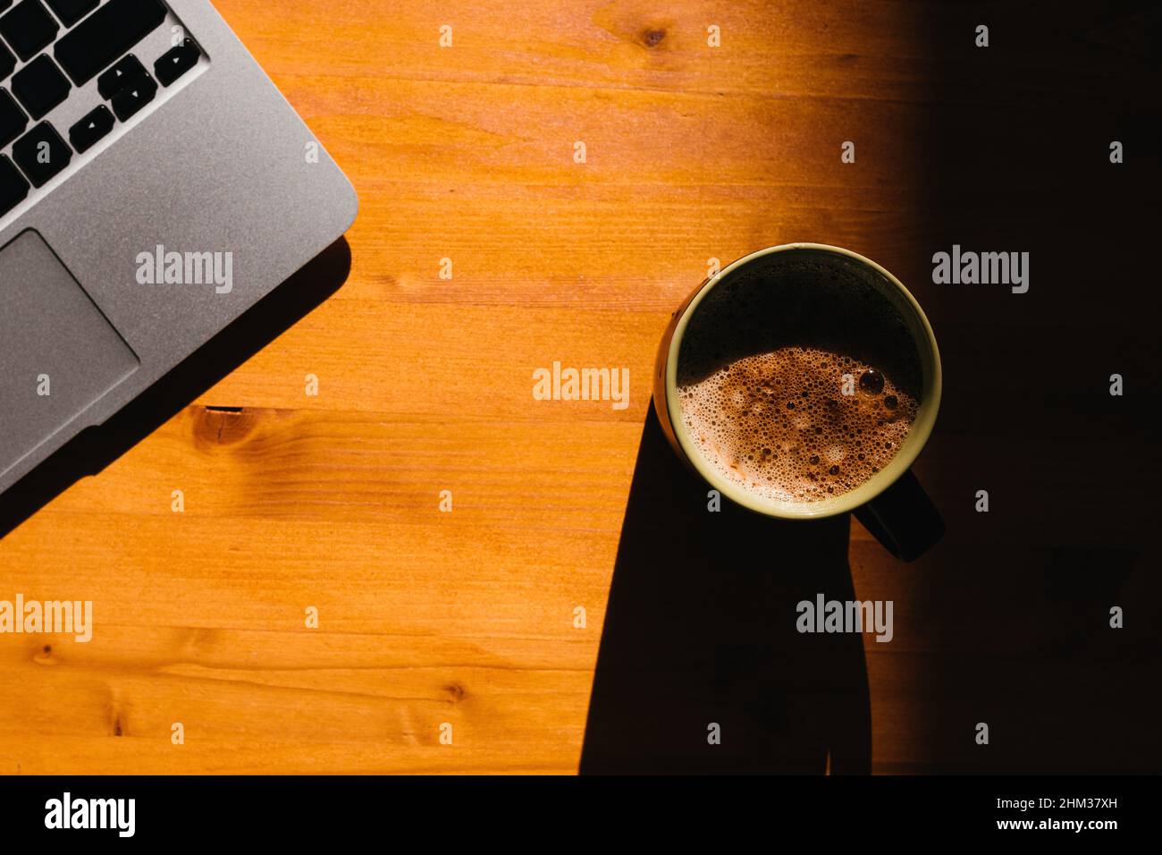 Pausa caffè in ufficio, computer portatile e tazza di caffè sulla scrivania, vista dall'alto con focus selettivo Foto Stock