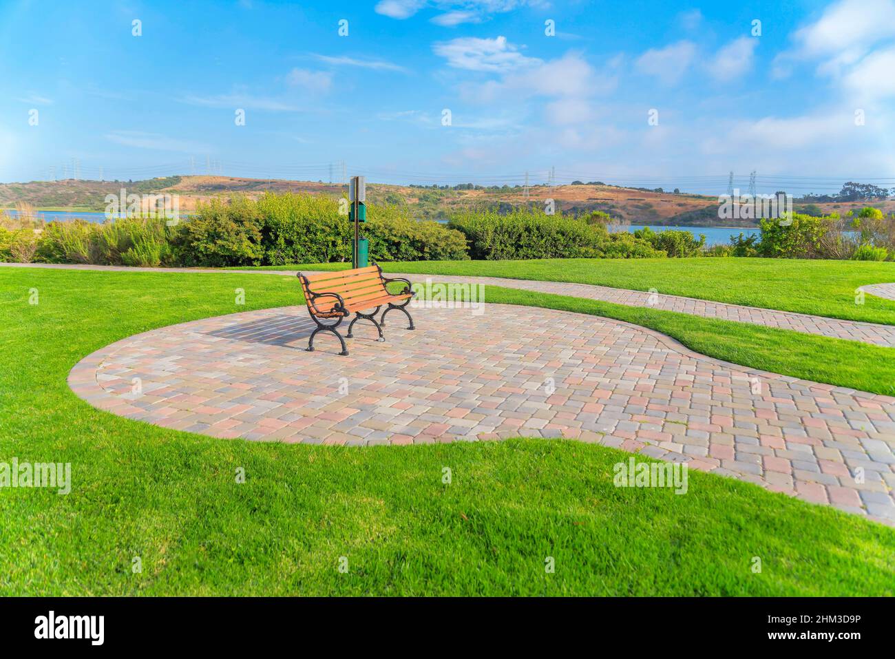 Panca giardino su un terreno in mattoni di pietra vicino alla Laguna di Agua Hedionda a Carlsbad, San Diego, CA Foto Stock