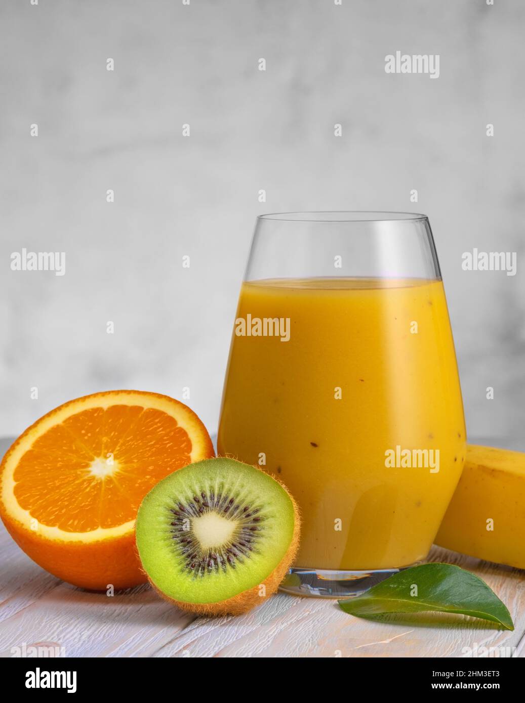 Bicchiere di banana verde, arancia e kiwi sani frullati. Foto Stock