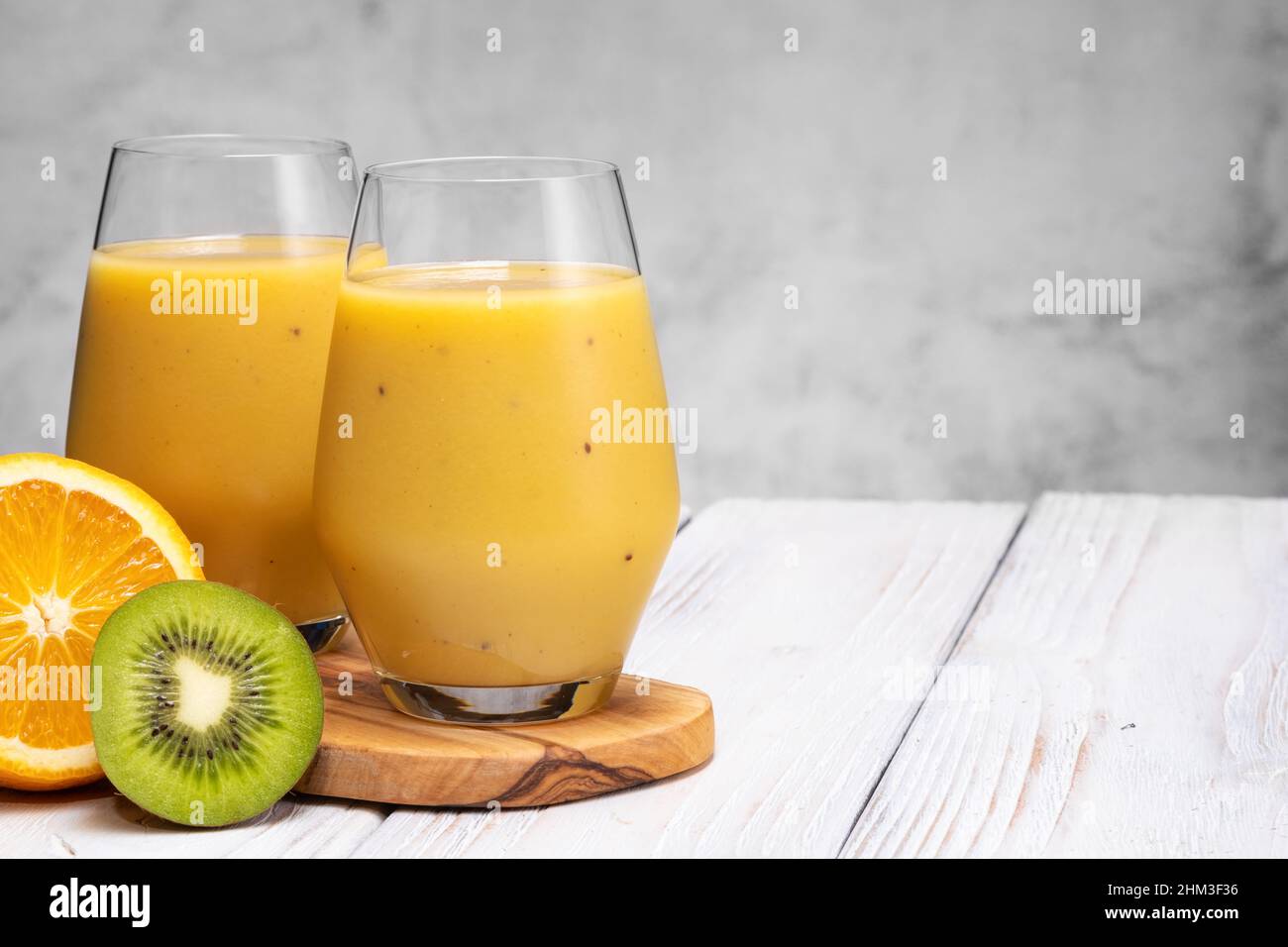 Bicchiere di banana verde, arancia e kiwi sani frullati. Foto Stock