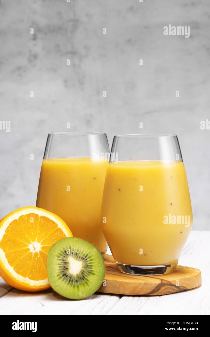 Bicchiere di banana verde, arancia e kiwi sani frullati. Foto Stock