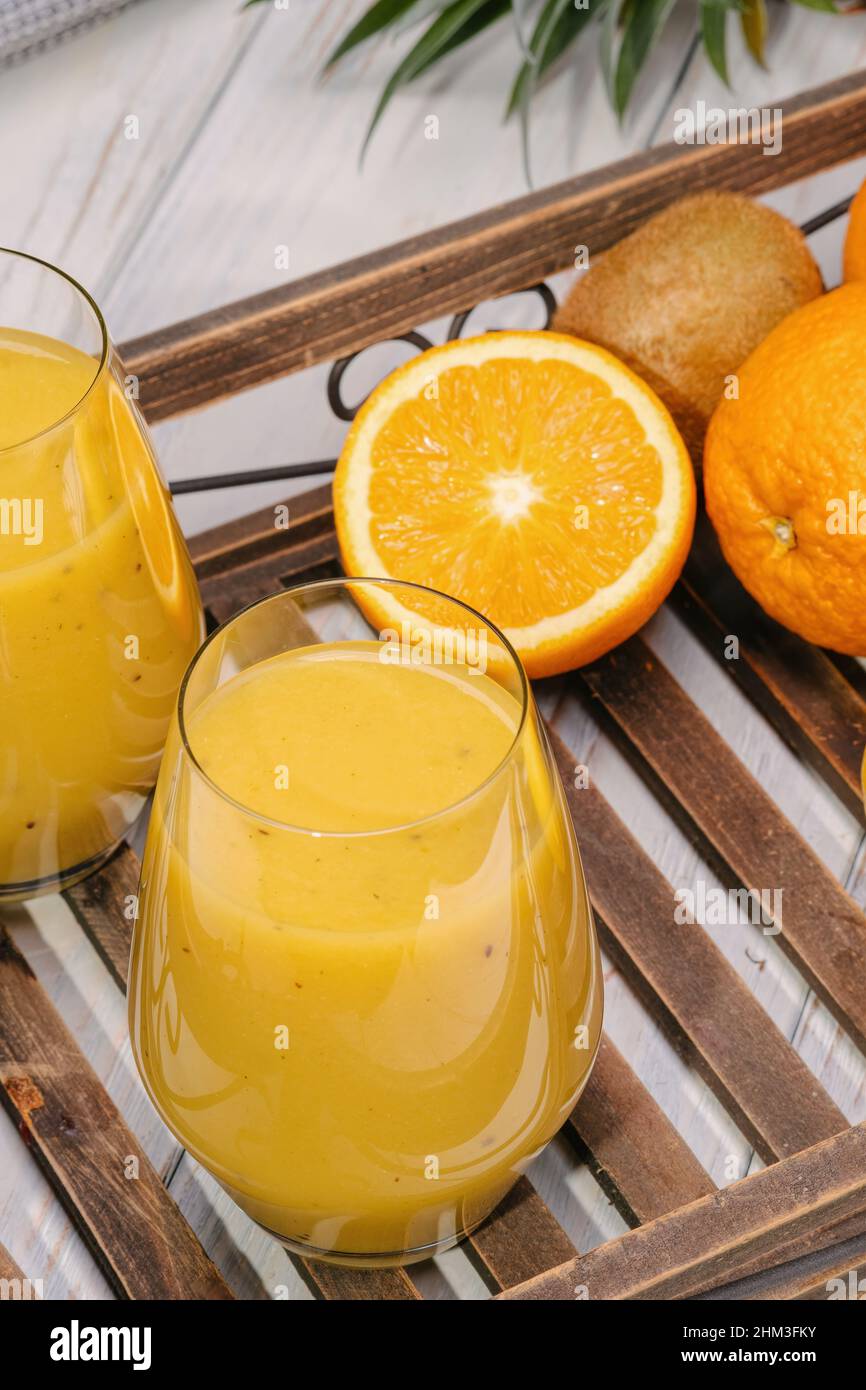 Bicchiere di banana verde, arancia e kiwi sani frullati. Foto Stock