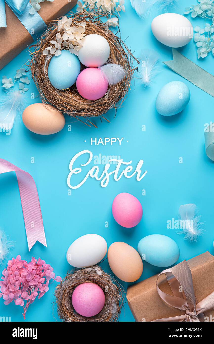 Buona Pasqua, sfondo festivo con uova colorate, nido e regali su sfondo blu con iscrizione. Vista verticale. Pasqua, sfondo primaverile. Foto Stock