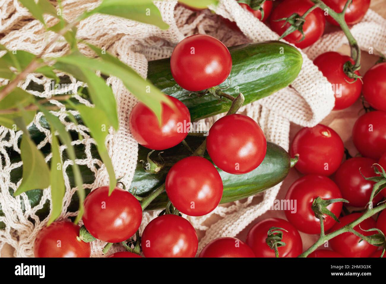 I pomodori rossi maturi e i cetrioli freschi si trovano in un sacchetto a rete. Vista dall'alto. Cibo sano fresco e concetto di dieta Foto Stock