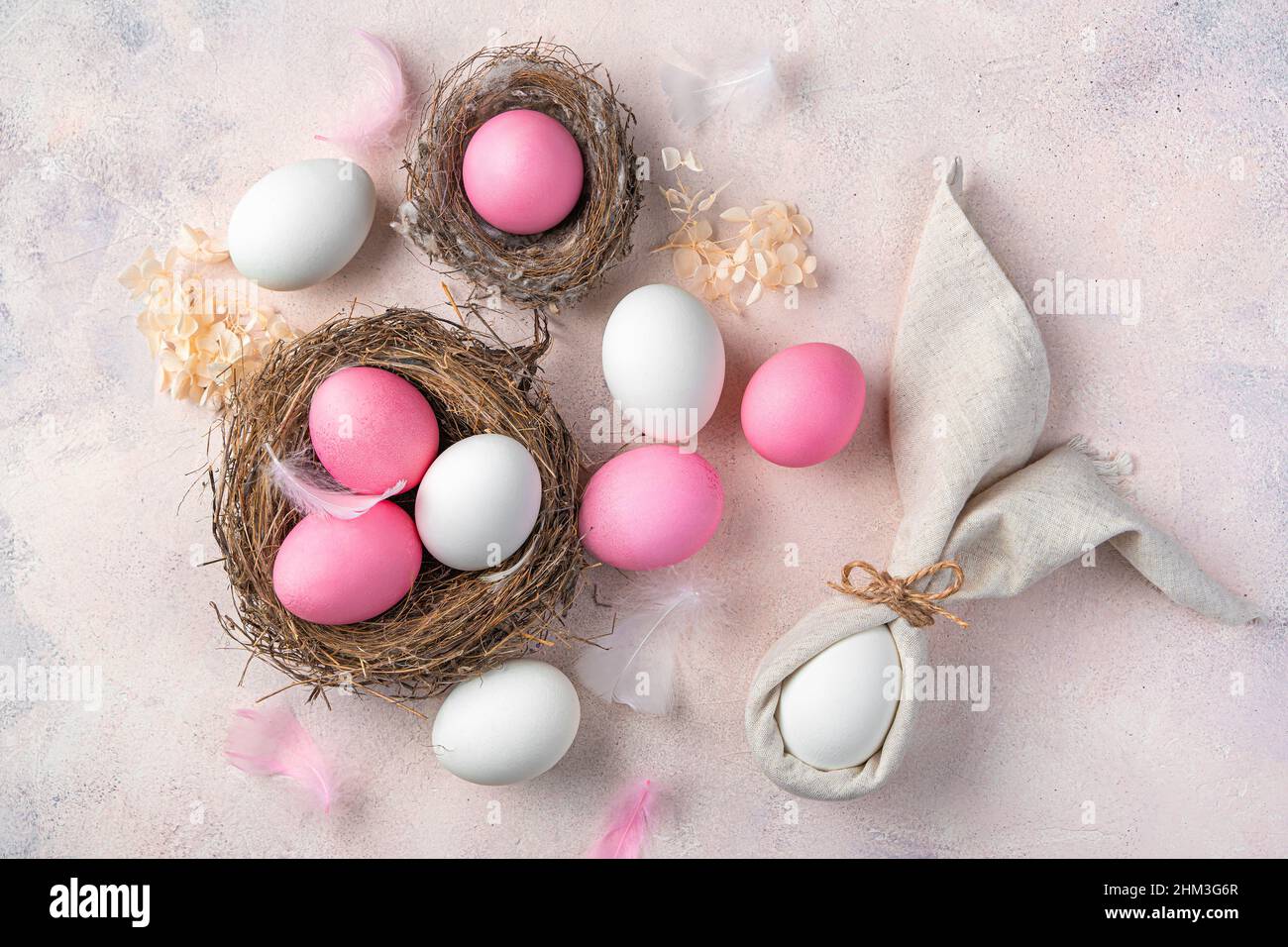 Delicato sfondo pasquale con un coniglio da tovagliolo e uova rosa e bianche su un delicato sfondo rosa. Vista dall'alto. Il concetto di Buona Pasqua. Foto Stock