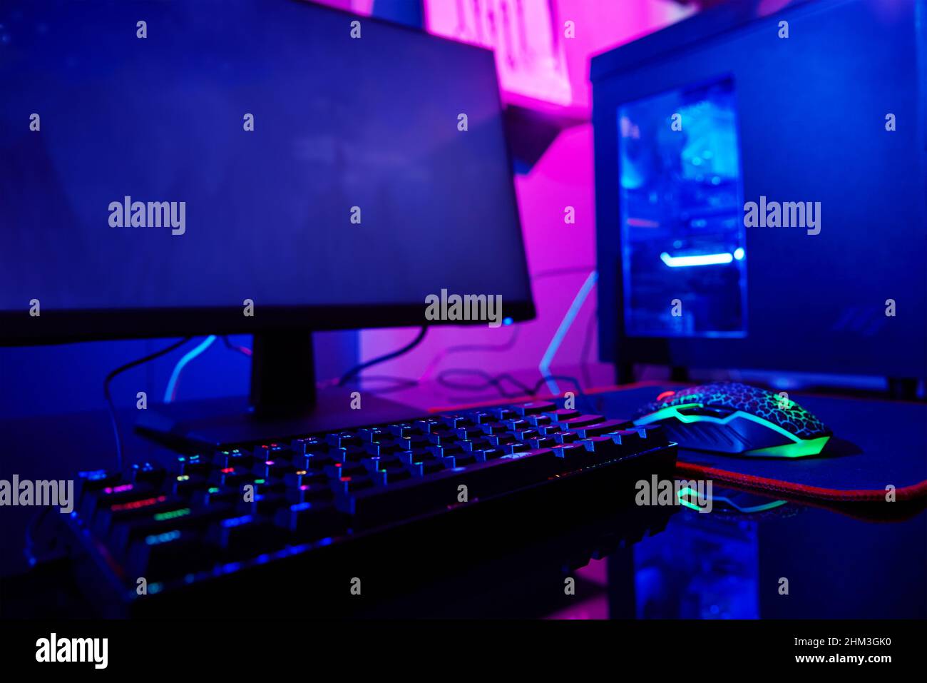 PC con tastiera rgb per videogiochi con sfondo neon colorato, stanza oscura con spazio di lavoro senza persone Foto Stock