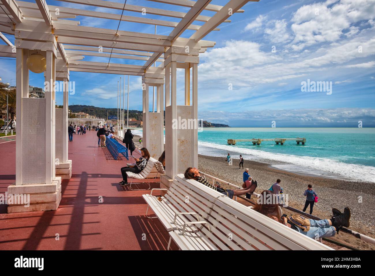 Nizza, Francia - 13 aprile 2018: Persone sulla famosa Promenade des Anglais e la spiaggia sulla Costa Azzurra vicino al Mar Mediterraneo in giornata di sole. Foto Stock