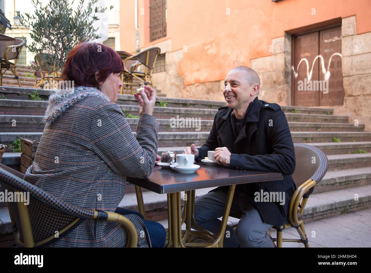 donna anziana che mangia il pan di spagna con il suo partner ad un tavolo da ristorante Foto Stock