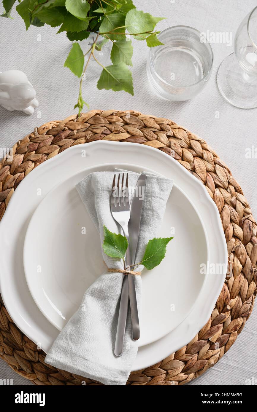 Pasqua elegante tavolo con coniglietto, verde fresco su tovaglia di lino bianco. Vista dall'alto. Tradizione religiosa cristiana. Foto Stock