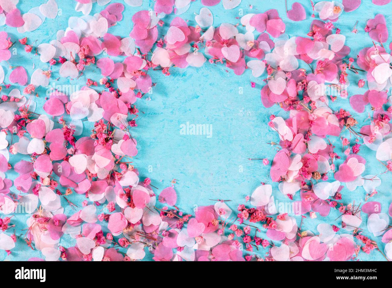Sfondo San Valentino con cuori di carta rosa e fiori di rosa confetti, un piatto adagiarsi su sfondo blu con un posto per il testo, una cornice per un biglietto d'auguri Foto Stock