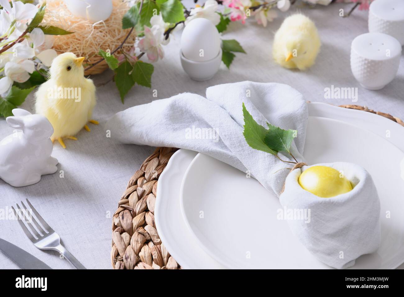 Tavolo di Pasqua e cena con pulcino giallo, decorazioni natalizie, fiori freschi e uova. Primo piano. Foto Stock