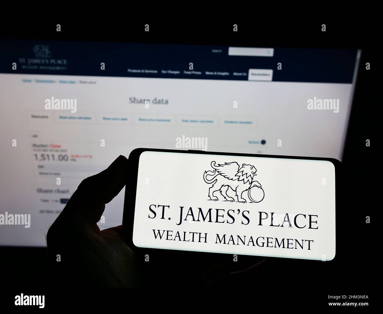 Persona che tiene il telefono cellulare con il logo della società britannica St. James's Place plc sullo schermo di fronte alla pagina web aziendale. Mettere a fuoco sul display del telefono. Foto Stock