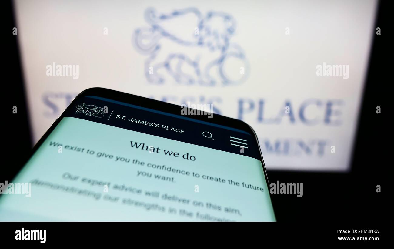 Telefono cellulare con sito web della società britannica St. James's Place plc sullo schermo di fronte al logo aziendale. Concentrarsi sulla parte superiore sinistra del display del telefono. Foto Stock