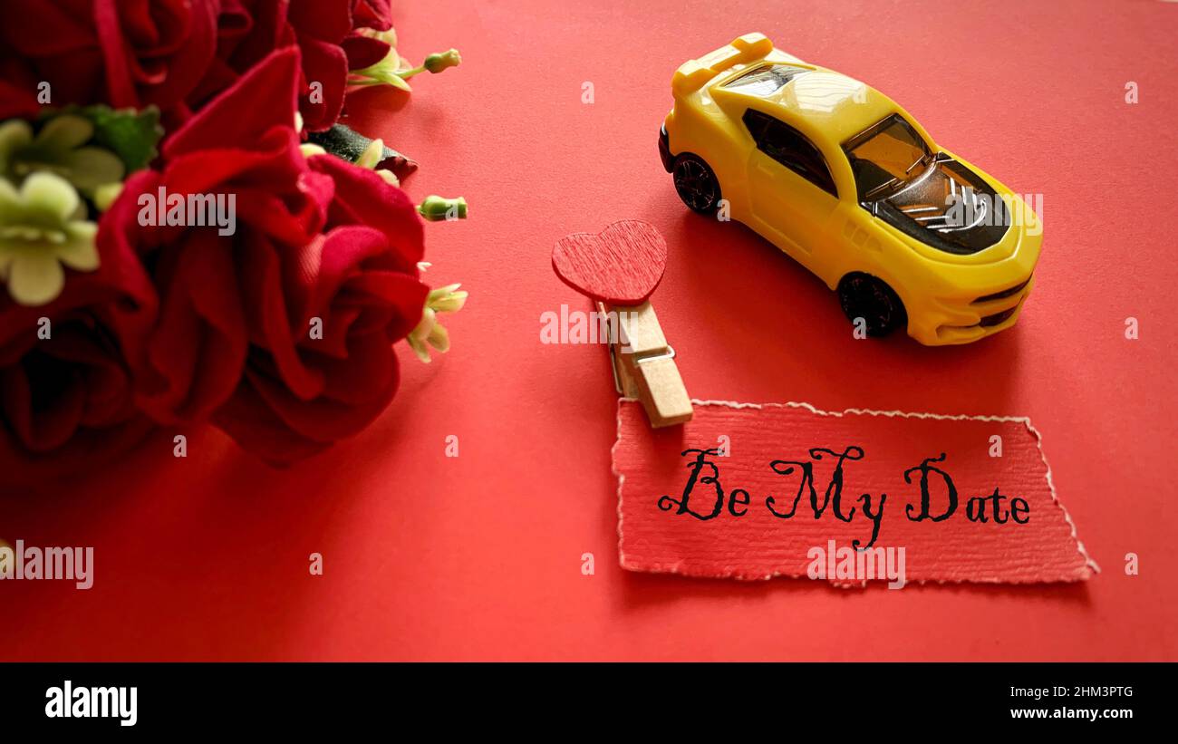 Sia il mio testo di data su carta rossa strappata con le rose e sfondo giallo dell'automobile del giocattolo. Buon San Valentino concetto. Foto Stock