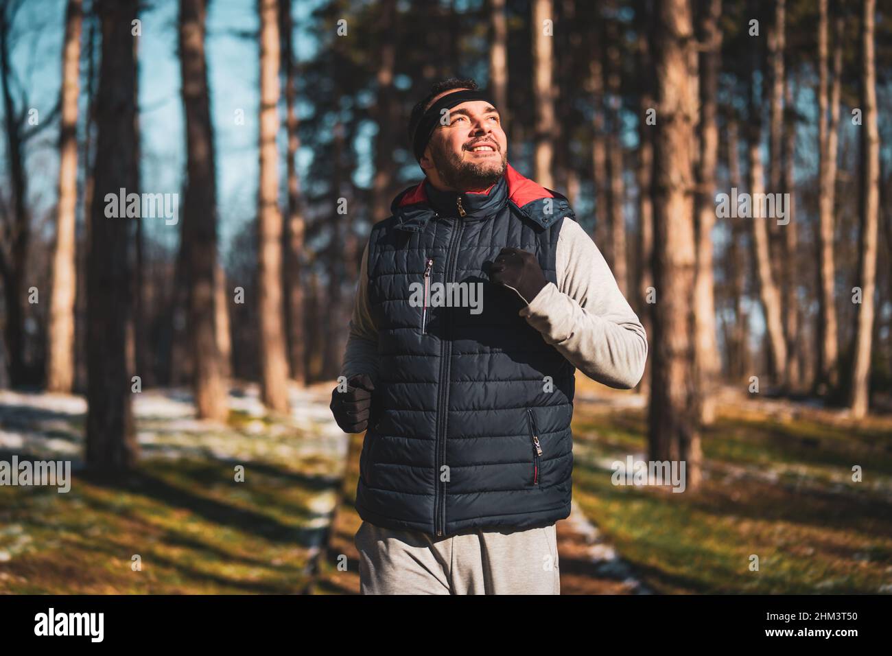 L'uomo adulto felice sta facendo jogging nel parco in inverno freddo giorno di sole. Foto Stock