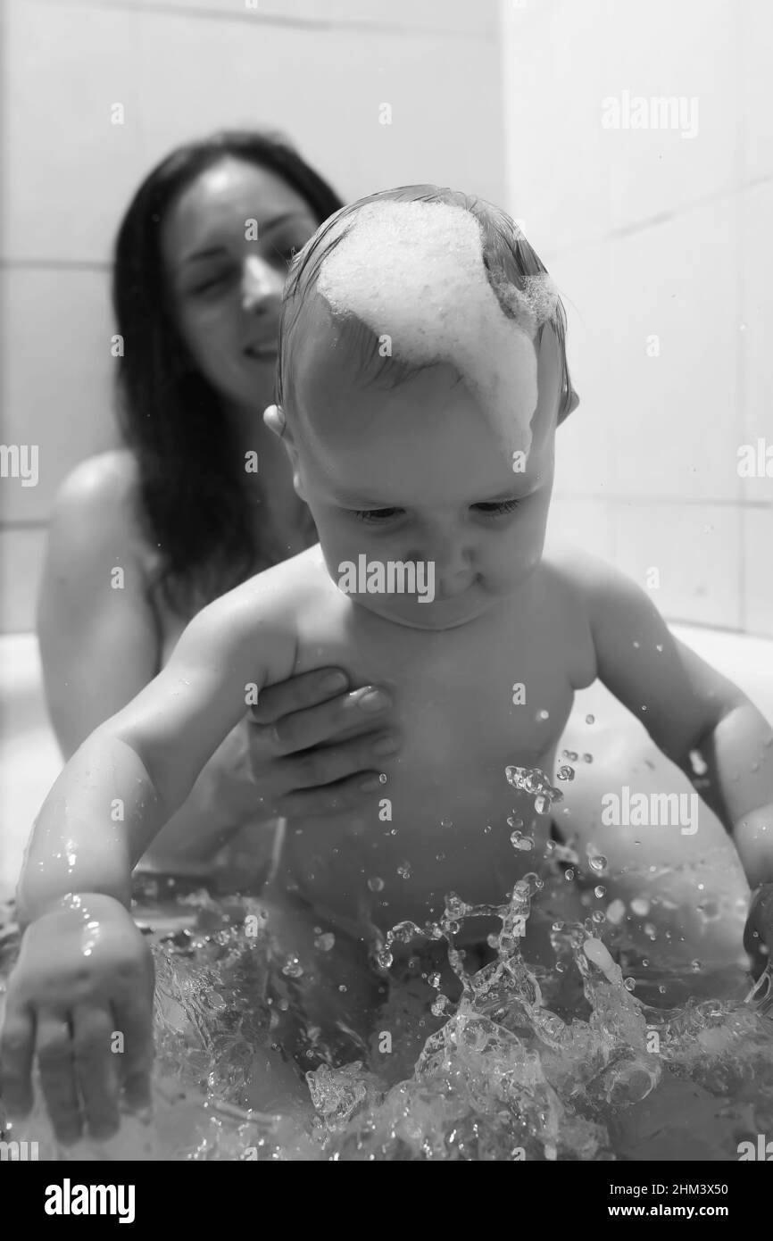 La mamma lava i bambini. Mamma e bambini stanno prendendo le procedure  dell'acqua in bagno. Schiuma, spray Foto stock - Alamy
