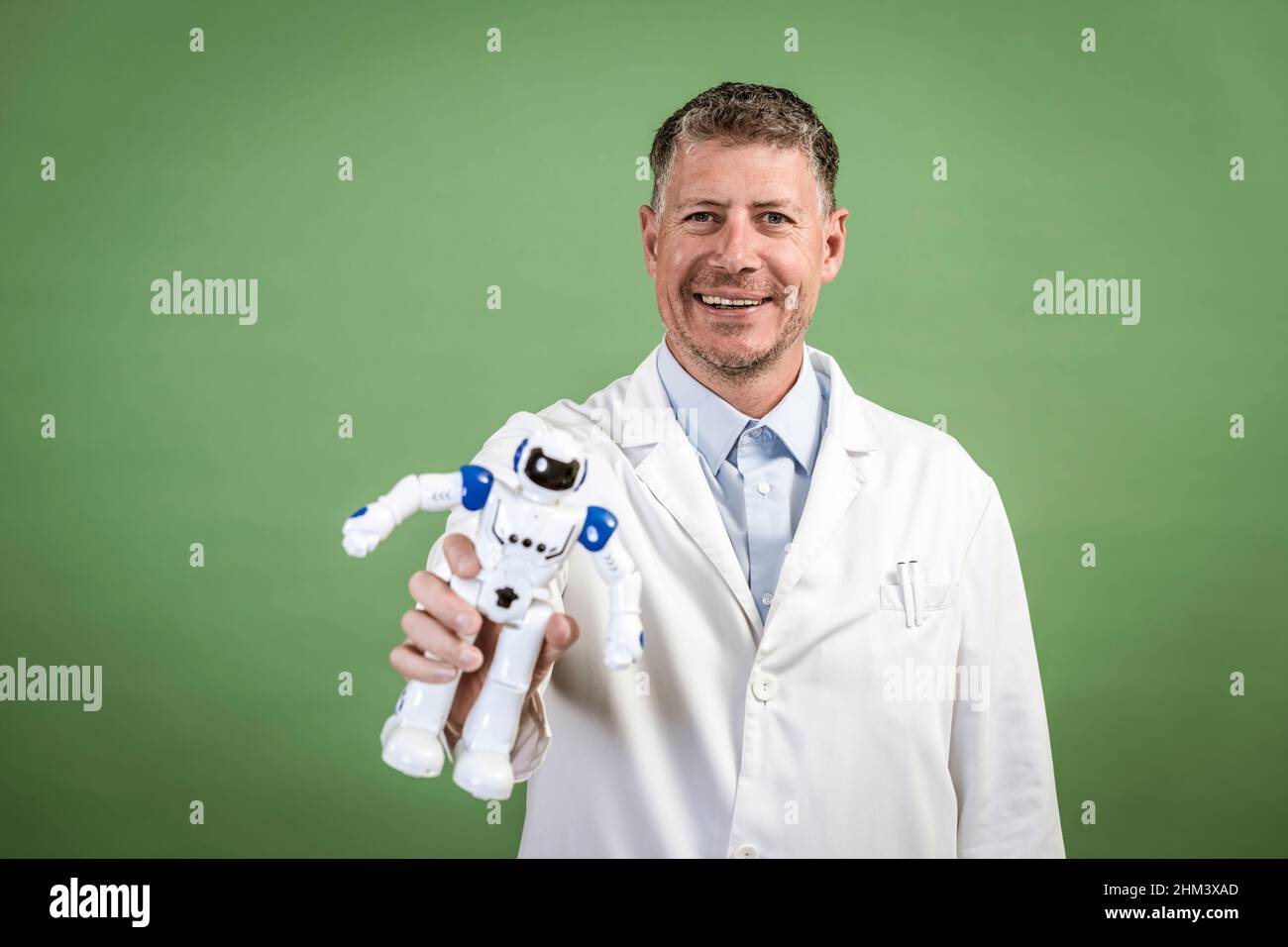 Scienziato con cappotto bianco tiene in mano un piccolo robot bianco e si  alza davanti a sfondo verde Foto stock - Alamy