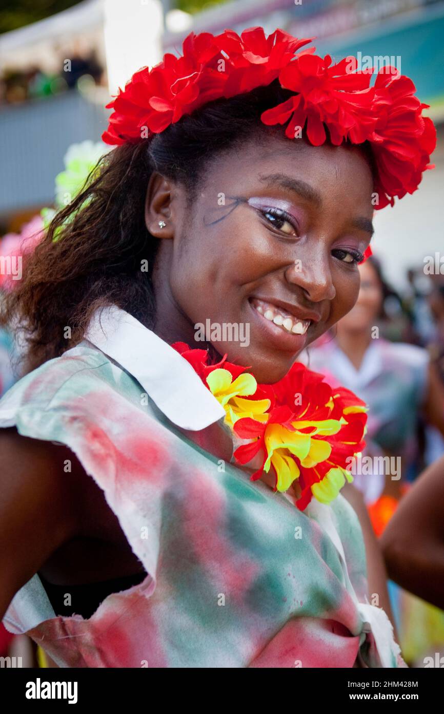 Ritratto di giovane donna sorridente e che indossa una ghirlanda di fiori mentre si esibisce per strada durante il Carnevale alle Seychelles. Foto Stock