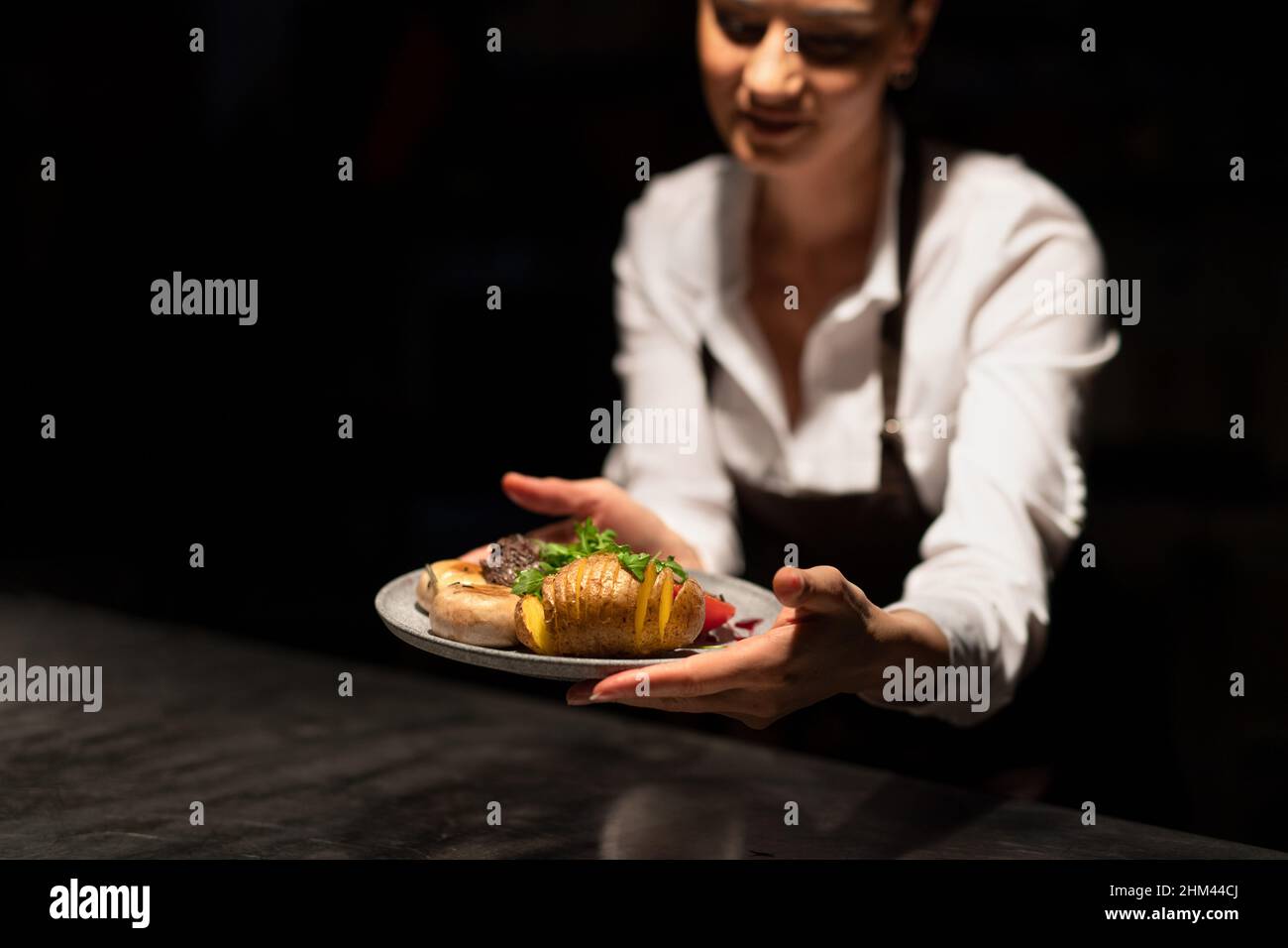 Piatto di consegna dello chef con pasto attraverso la stazione di ordinazione nella cucina commerciale su sfondo nero. Foto Stock