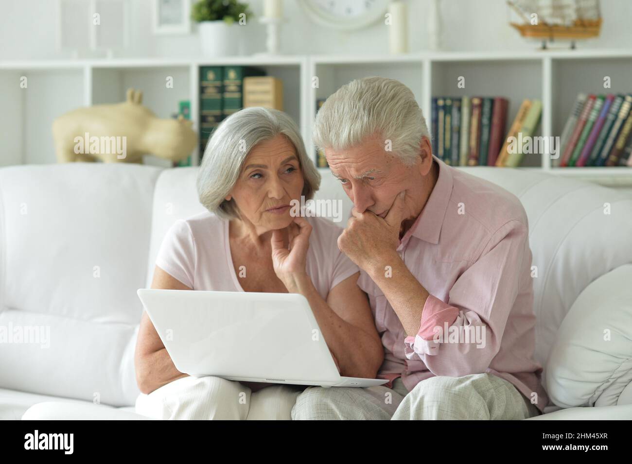 Due anziani seduti sul divano con computer portatile Foto Stock